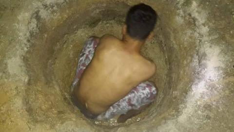 A detainee on Manus Island digging a hole in the ground to find water