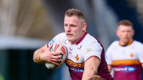 Tom Burgess carries the ball into contact under his right arm for Huddersfield Giants