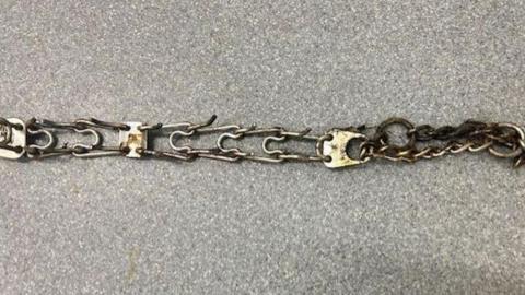 A stained barbed metal chain on a grey background.
