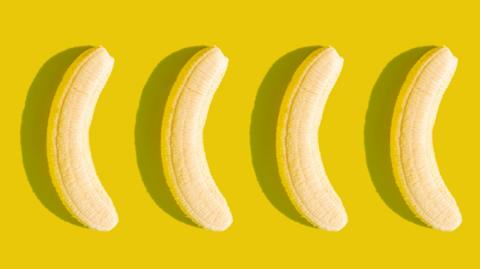 Four peeled bananas lined up on a yellow background