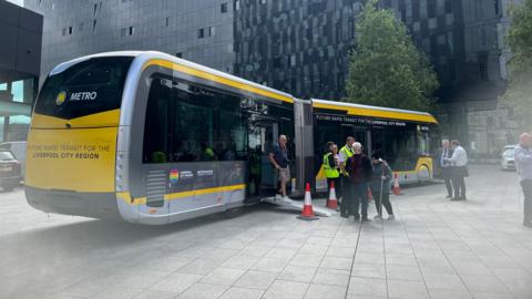 People looking at the new yellow 59ft (18m) long single-decker rapid transit vehicles - known as gliders in Belfast - in Liverpool city centre.
