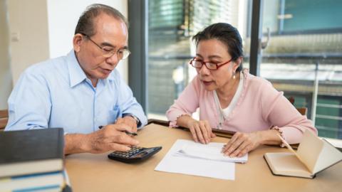 An elderly couple looking at bills with their calculator out