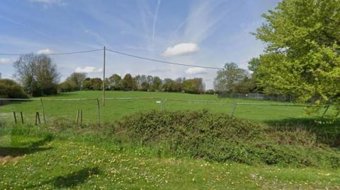 Fence in front of a green field
