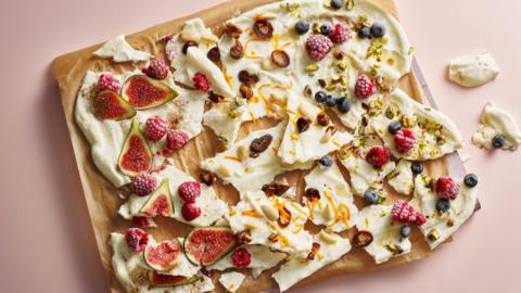 Yoghurt bark with figs, blueberries, raspberries and nuts on a wooden board