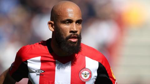 Bryan Mbeumo wears a red and white striped Brentford shirt during a football match