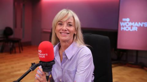 A woman, Tamzin Outhwaite, has shoulder-length blonde hair and is wearing a lilac shirt.
