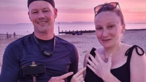 metal detectorist and woman on sandy beach