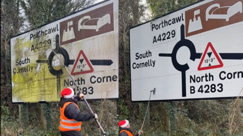 Cleaning road signs wearing a santa hat