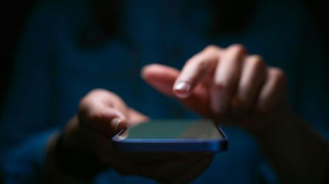 A file photo showing blurred female hands holding a mobile phone.