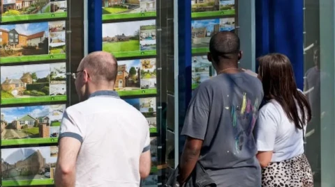 three people looking in an estate agents window