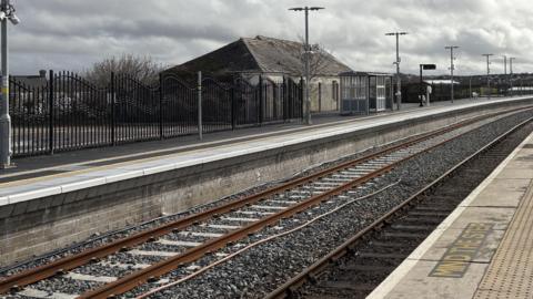 Newquay railway station's new track and platform heading off into the distance with a bus shelter and lighting on the platform 