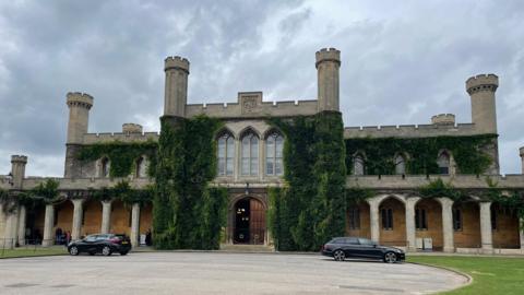 The exterior of Lincoln Crown Court, a former castle, it is covered in greenery and has arches and turrets.