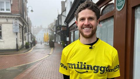 James Cooper, wearing a yellow t-shirt, poses for a picture in East Grinstead.