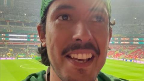 Mexican football fan, wearing green national kit looking optimistic, taking a selfie