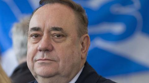 Alex Salmond in extreme close-up looking towards the camera. There is a 'Yes' flag behind him.