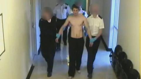 Allan Marshall being led by prison officers whose faces are blurred