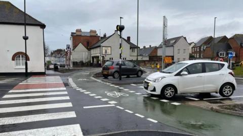 Cars on a roundabout with dedicated cycle lane and pedestrian crossing
