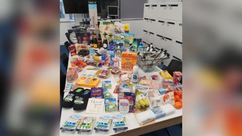 A table full of groceries including slippers and a thank you card