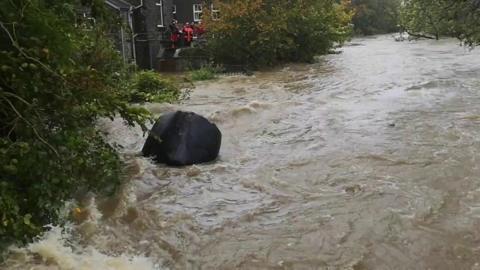 A silage bale in a fast-flowing river