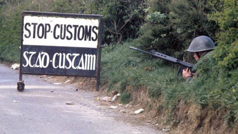 A soldier looking towards the Irish side of the Irish/UK customs border in 1974