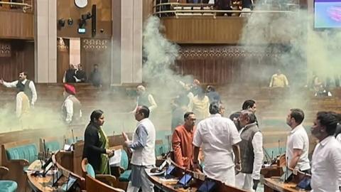A video grab taken from the India TV channel shows an unidentified man jumping from the visitor's gallery of Lok Sabha, causing a scene using a colour smoke in the House during the Winter Session of Parliament, in New Delhi on Wednesday.
