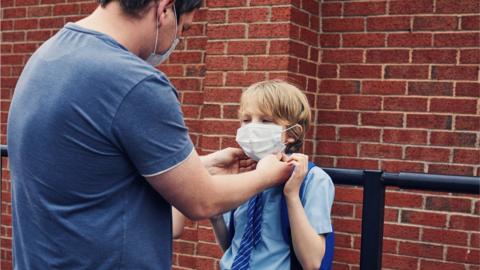 A man helping his son put a mask on