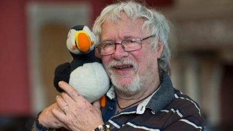 Bill Oddie holding a toy puffin
