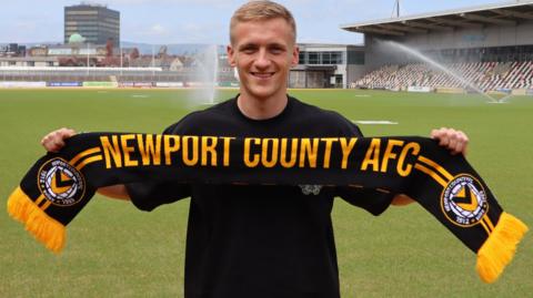 Matt Smith holds up a Newport scarf