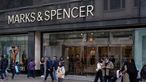 People standing outside and walking past at a M&S store in London