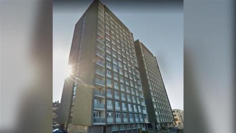 Two beige and white tower block buildings side-by-side.