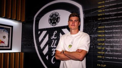 Jaka Bijol stands in front of Leeds badge after signing