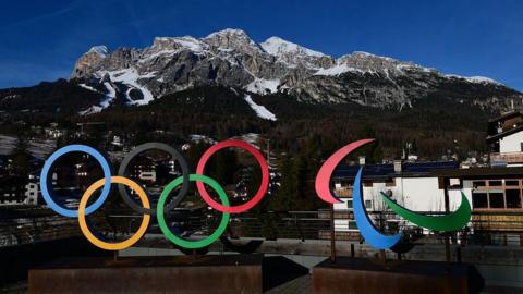 A picture showing the logo of Milano Cortina 2026 Olympic and Paralympic Games with the Women's Alpine skiing Olympia delle Tofane slope in the background in the distance in Cortina d'Ampezzo.