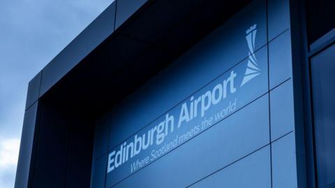 A general view of Edinburgh Airport. The name of the building is in white on a grey background. It is an overcast day.