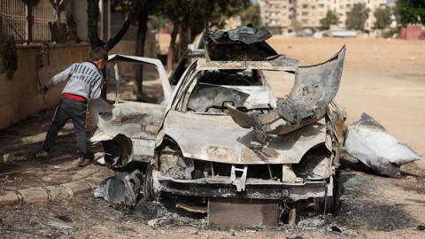 A Syrian boy checks a destroyed vehicle in Ashrafiyat Sahnaya near Damascus on 1 May 2025