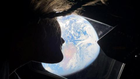  NASA astronaut and Artemis II mission specialist Christina Koch peers out of one of the Orion spacecraft's main cabin windows, looking back at Earth