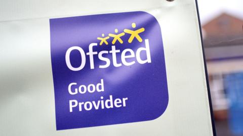 Ofsted sign which reads 'Ofsted Good Provider' written in white on a purple background with yellow stars on it.