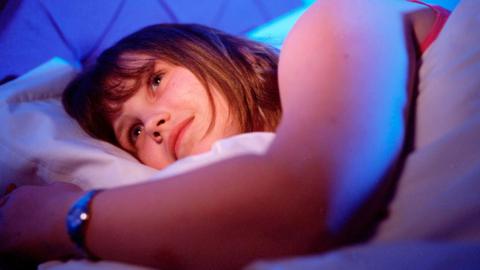 Young woman lying awake in bed