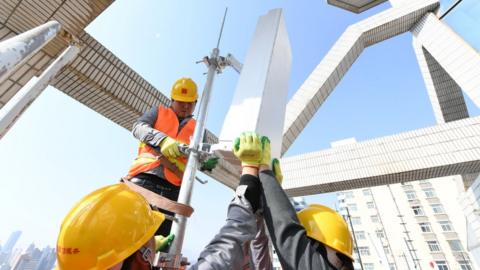 Workers fitting a 5G base station in China