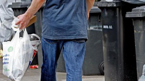 Man taking rubbish into bins