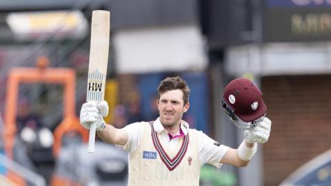 Craig Overton with helmet in one hand and bat in the other to acknowledge a century