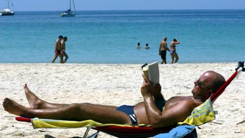 A tourist rests on a lounger on a beach in Phuket