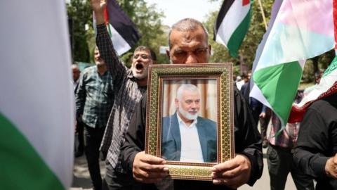 A man carrying a picture of Ismail Haniyeh