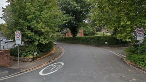 A street view image of Clifton Road in Exeter. It has 20mph signs and writing on the road. 