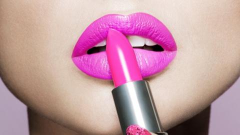 Close up woman applying pink lipstick