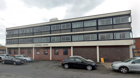 The exterior of Windmill House which is a two storey black and white building.