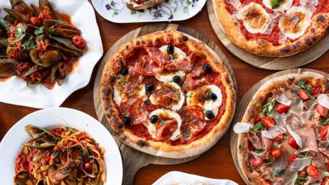 A variety of pizza and pasta on a table