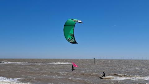 Sunny, blue skies by the beach with kite surfers in Essex