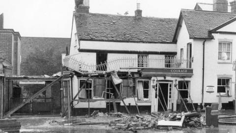 A black and white image of a pub in Guildford with the front badly damaged from a bomb blast. 