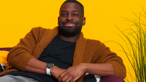 A person smiling and lounging on a sofa.