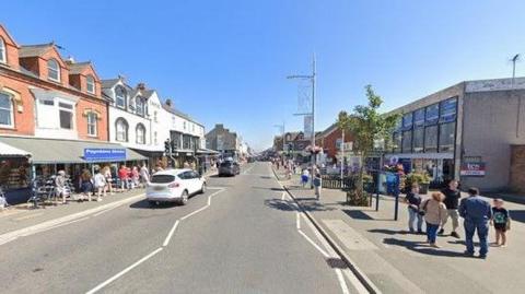 Google street view of Mablethorpe high street with a few cars along the high street and several people walking along the streets